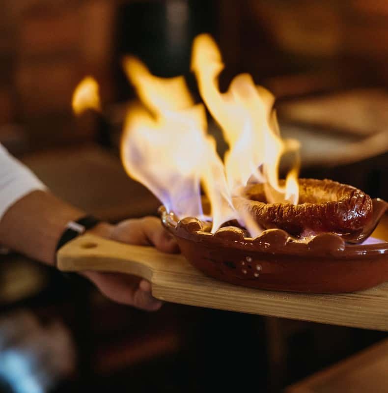Chouriço assado flaming on its clay dish