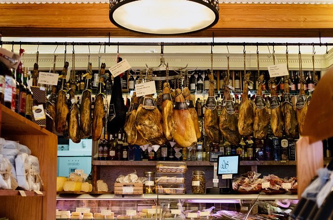 Cured hams hanging over the counter of a Lisbon grocer